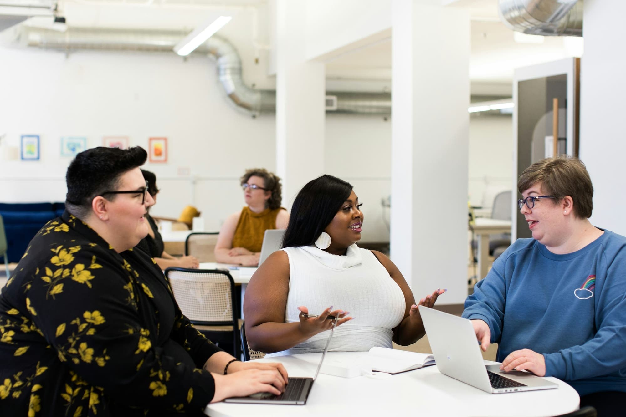 A team talking around a table with laptops in a bright office